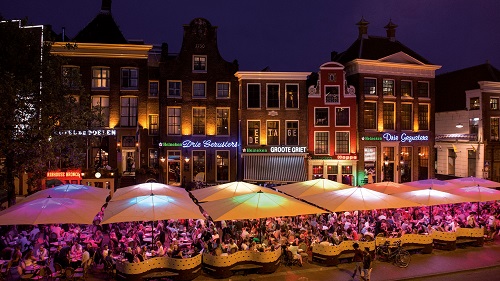 guests sitting outside of the bars under plus-size illuminated parasols 